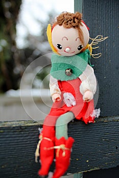Christmas Elf on a Shelf Outdoors Sitting on wood fencing