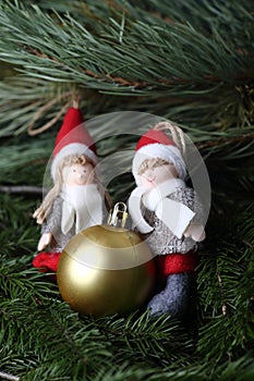 Christmas elves - a boy and a girl with christmas gift on fur tree brunches. Winter concept