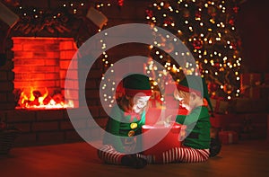 Christmas. elves with a magic gift near Christmas tree and fireplace