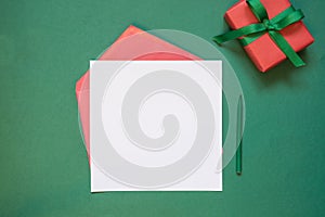 Christmas empty blank letter to Santa or invitation with giftbox on green. Top view