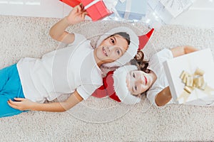Christmas Eve. Boy and girl of younger school age lie on a floor near the decorated Christmas tree. top view