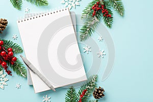 Christmas Eve concept. Top view photo of notepad pen spruce branches in hoarfrost pine cones mistletoe berries and snowflakes on