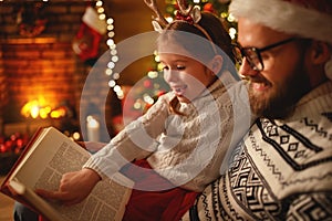 Christmas Eve. family father and child reading magic book at home