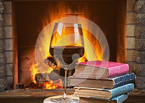 Christmas eve.Glass of Red wine and old books near a cozy fireplace