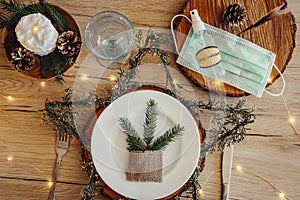 Christmas eve holiday party decorated table set with disposable medical mask and alcohol hand sanitizer bottle.