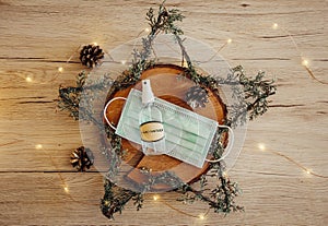 Christmas eve holiday party decorated table set with disposable medical mask and alcohol hand sanitizer bottle.