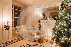 Christmas evening by candlelight. classic apartments with a white fireplace, decorated tree, bright sofa, large windows