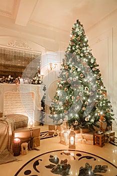 Christmas evening by candlelight. classic apartments with a white fireplace, decorated tree, bright sofa, large windows