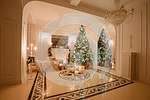 Christmas evening by candlelight. classic apartments with a white fireplace, decorated tree, bright sofa, large windows