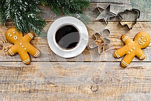 Christmas evening. Gingerbread man, coffee and spruce branch on wooden background top view copyspace