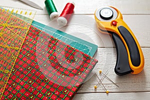 Christmas fabric and ruler on craft mat surrounded quilting and sewing accessories