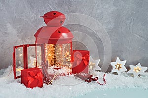 Christmas fairy composition of red lantern with Christmas tree and lights inside, decorative skis, sledges with