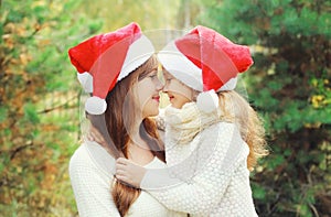 Christmas and family concept - child and mother in santa red hats