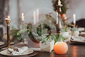 Christmas Family Dinner Table Concept. Candles, vintage dishes, fir branches with clear copy space on wall