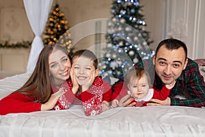 Christmas family Happy mom,dad and little daughter and son, lying down. Enjoyng love hugs, holidays people. Togetherness concept