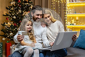 Christmas family, husband wife and little daughter for Christmas at home make online shopping in online store remotely