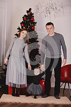 Christmas family kissing and hugging. Child surprised his mother and father with a Christmas gift. Family near christmas tree.