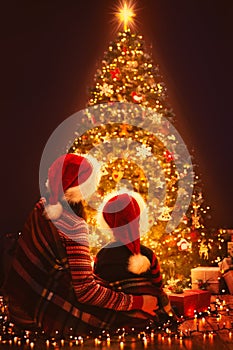 Christmas Family Looking Lighting Xmas Tree, Mother and Child in Red Santa Hats, New Year Night