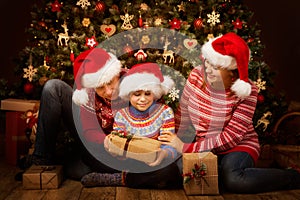 Familia abrir de Navidad un árbol feliz padres en sombreros 