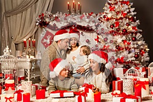 Christmas Family opening Presents. Family with Kids in Santa Hats next to Christmas Tree with White Gift Boxes. Xmas Home Room