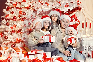 Christmas Family Portrait, Parents with Children in Santa Hats with Presents Gift Boxes in Home, White Xmas Tree