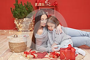 Christmas family. Red Merry Christmas tree background. Woman mother and child daughter celebrate new year. Xmas greeting card.