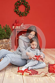 Christmas family. Red Merry Christmas tree background. Woman mother and child daughter celebrate new year. Xmas greeting card.