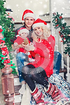 Christmas family smiling near the Xmas tree. Living room decorated by Christmas tree and present gift box