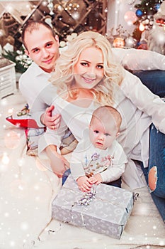 Christmas family smiling near the Xmas tree. Living room decorated by Christmas tree and present gift box