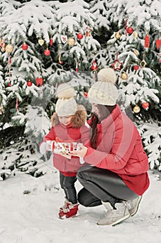 Christmas family in winter park. Happy family mother and child daughter having fun, playing at winter walk outdoors. Outdoor