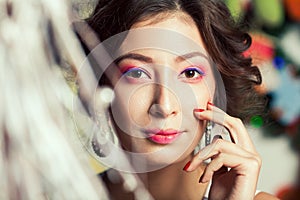 Christmas fashion beauty concept. Portrait of young brunette with arty make-up wearing luxurious vintage diamond earrings and