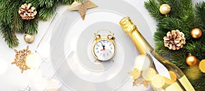 Christmas festive background with champagne bottle and wine glasses, golden christmas balls, alarm clock, fir branches and decor,