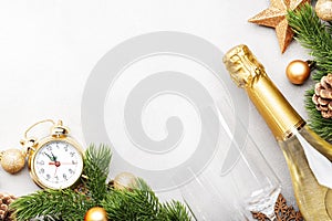 Christmas festive background with champagne bottle and wine glasses, golden christmas balls, fir branches, alarm clock and decor,