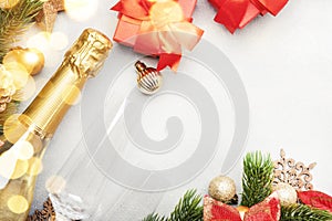 Christmas festive background with champagne bottle and wine glasses, red gift boxes, golden christmas balls, fir branches,