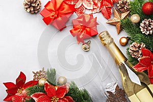 Christmas festive background with champagne bottle and wine glasses, red gift boxes, golden christmas balls, fir branches,