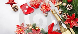 Christmas festive background with champagne bottle and wine glasses, red gift boxes, golden christmas balls, fir branches,