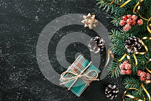 Christmas festive background with gift box, Christmas tree branches and seasonal decorations on black board. Flat lay. Space for