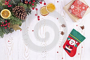 Christmas festive background with a red felt stocking with the image of Santa Claus, fir branches, cones and Christmas