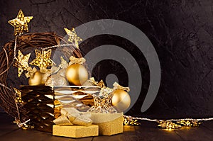 Christmas festive interior with gold glowing lights with stars, wreath, decoration, gift box with glitter ribbon on black plaster