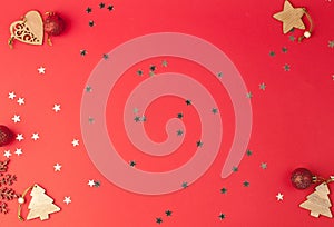 Christmas festive red background with a place for text on which glittering stars and wooden decorative ornaments and Christmas