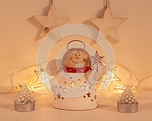 Christmas festive scenery showing an angel ornament in warm golden light; front view with blurred bokeh star lights background on