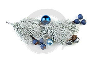 Christmas fir branch with silver baubles, blue berries and other ornaments isolated on white