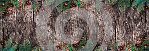 Christmas Fir branches with lights and red decorations on wooden background.