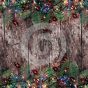 Christmas Fir branches with lights and red decorations on wooden background. Xmas and Happy New Year frame.