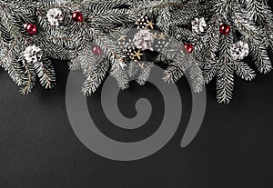 Christmas fir branches with pine cones, red decoration on dark background