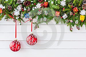 Christmas fir tree branch with decoration on white wooden board background. Top view, copy space.