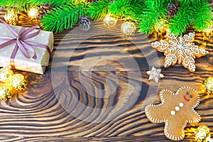 Christmas fir tree with homemade gingerbread cookies, gift and lights on old wooden background with space for text. Merry Christma