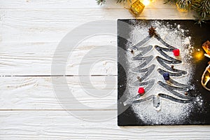 Christmas fir tree made from flour on the black on shale food board background on white wooden table. Top view, copy