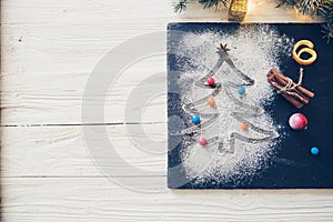 Christmas fir tree made from flour on the black on shale food board background on white wooden table. Top view, copy