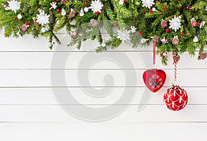 Christmas fir tree with red decoration on white wooden board background. Copy space.